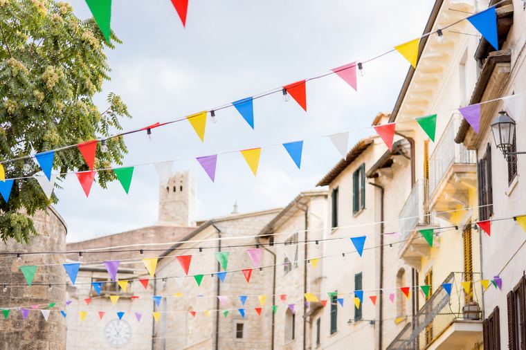 Luci decorative accese si riflettono su una pozzanghera lungo la strada della festa.