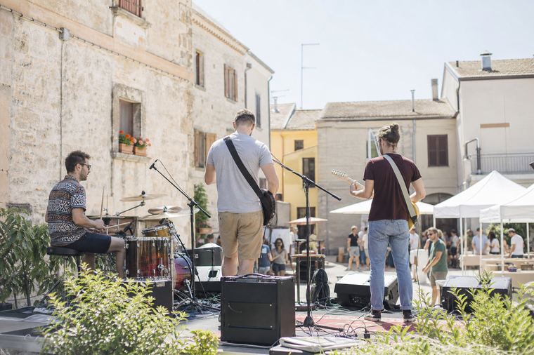 Un sassofonista suona sul palco di una serata estiva davanti al pubblico.
