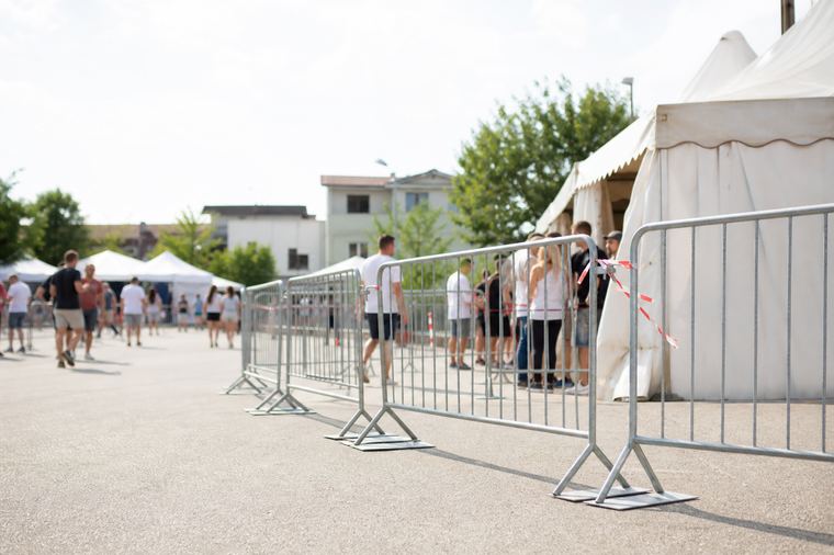 Il pubblico segue lo spettacolo serale all'aperto, ripreso di spalle tra le luci.