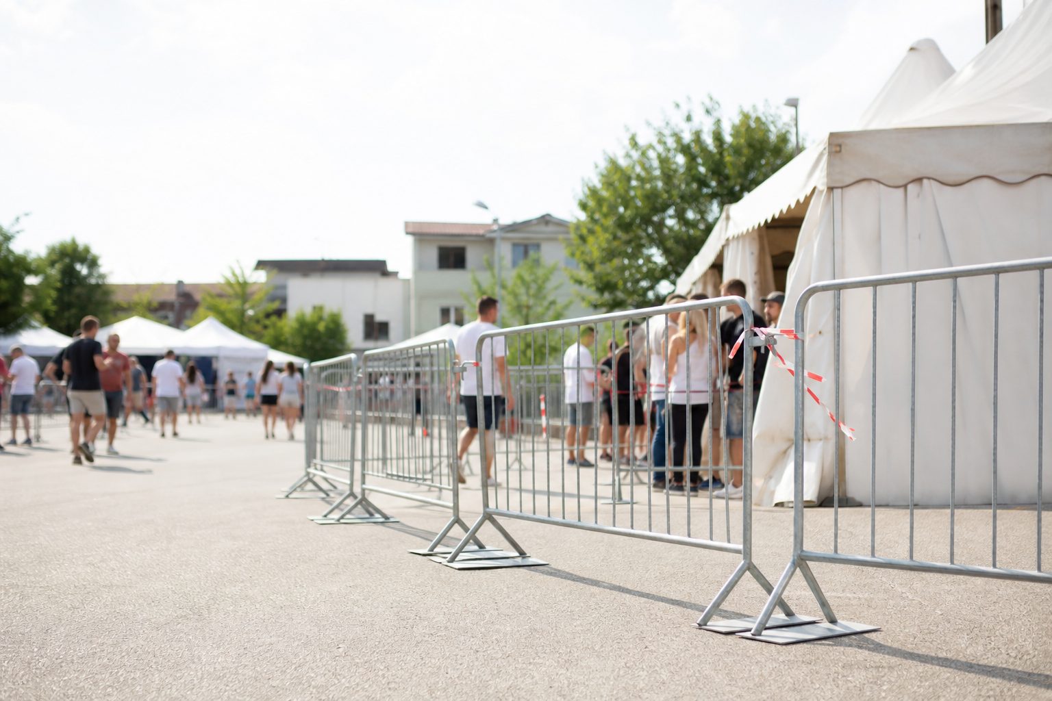 Il pubblico segue lo spettacolo serale all'aperto, ripreso di spalle tra le luci.